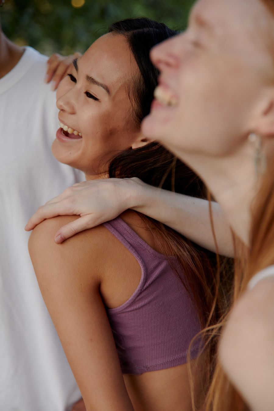 Drei junge Menschen lachen zusammen im Freien