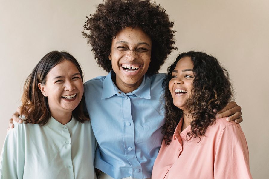 Drei Frauen lachen und stehen mit den Armen umeinander